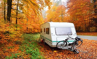 Old travel trailer in fall outdoor setting.