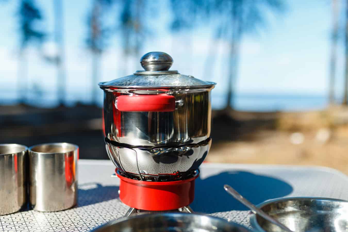 Camping coffee pot sits on outdoor table.