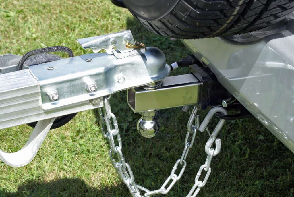 Close up of new trailer hitch on new vehicle with safety chains.