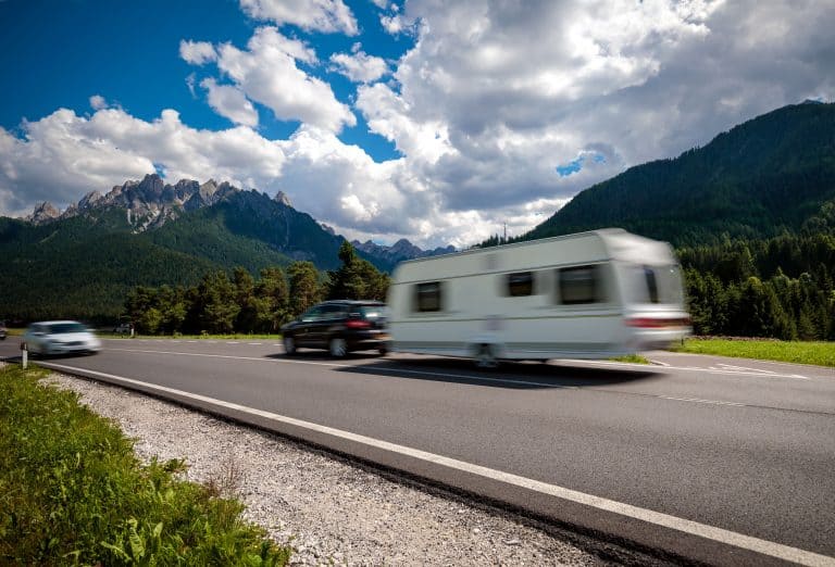 SUV pulls travel trailer on scenic highway.
