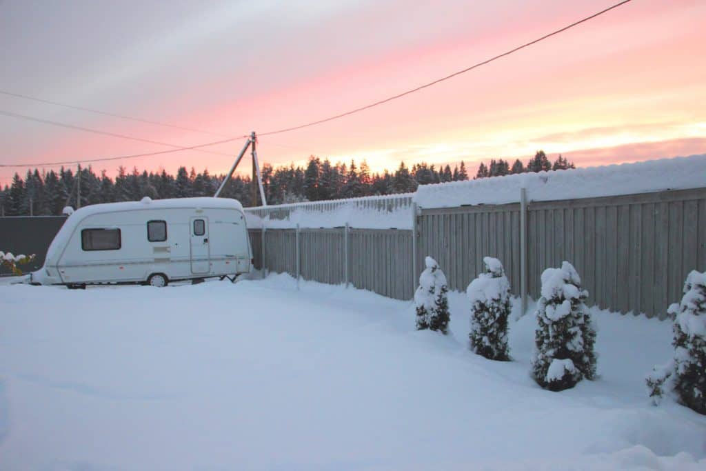 Uncovered travel trailer sits outdoors under a layer of snow.