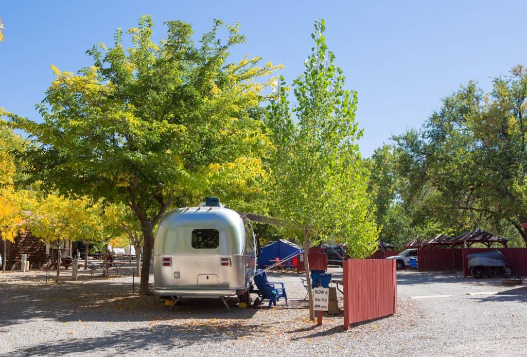 Airstream travel trailer at public campground with some tree cover.