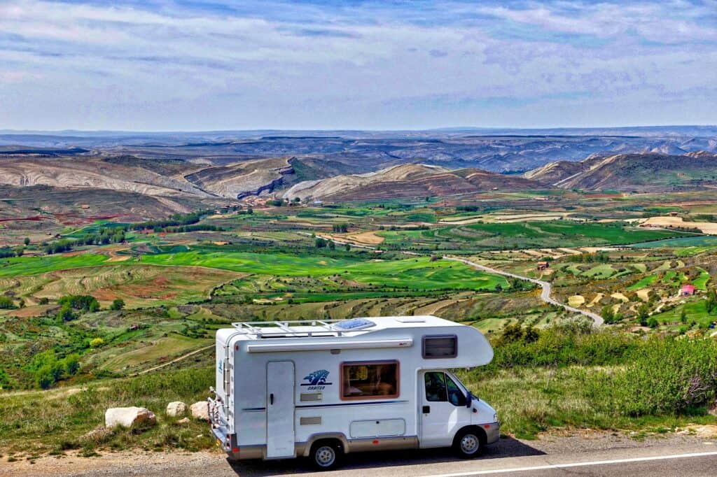 Class C motorhome in foreground of picturesque landscape.
