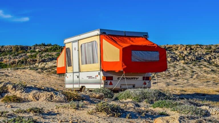 Pop-up camper fully extended in remote dry area.