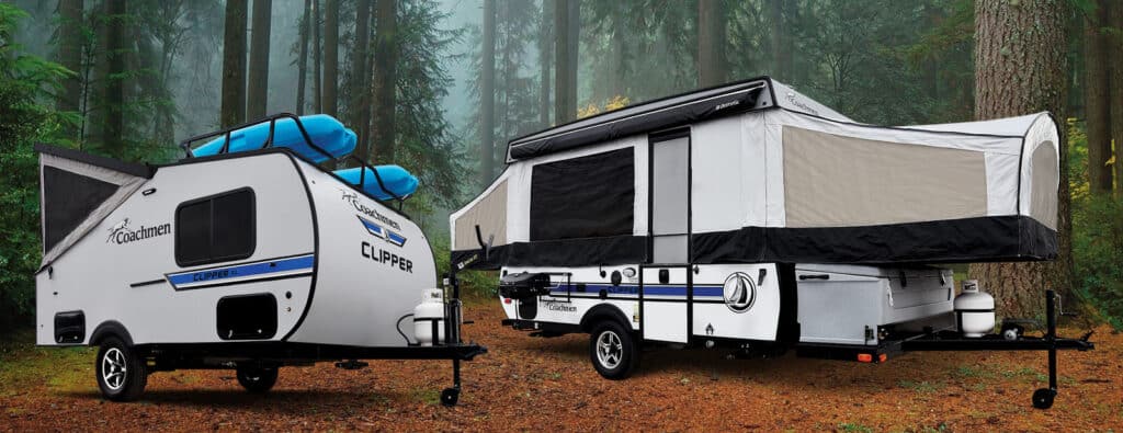 Two Coachmen pop-up campers setup in wooded campground.