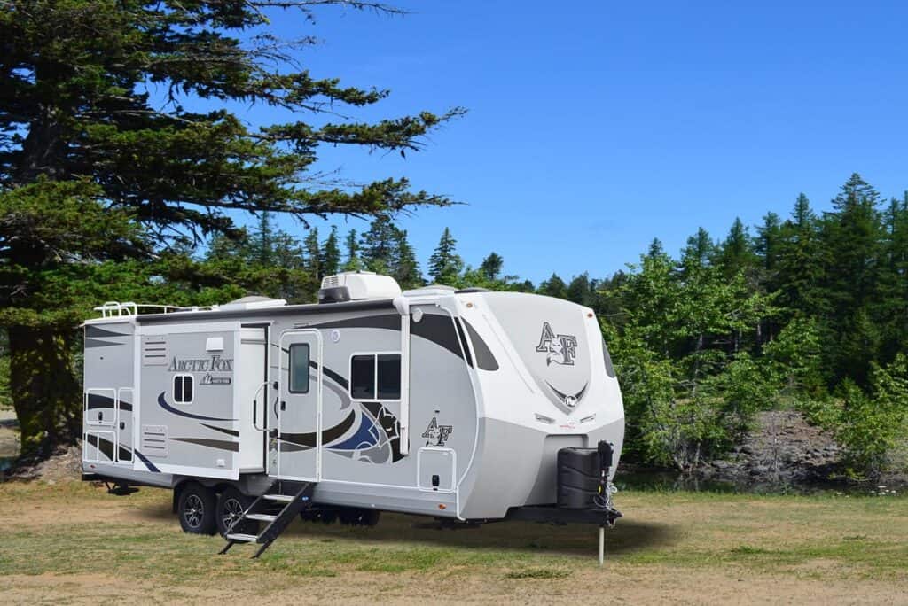 Arctic Fox 28ft. Travel Trailer parked near wooded area.