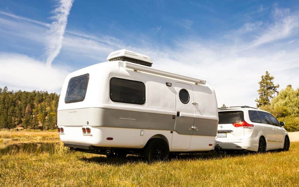 Minivan with fiberglass trailer attached in remote field.