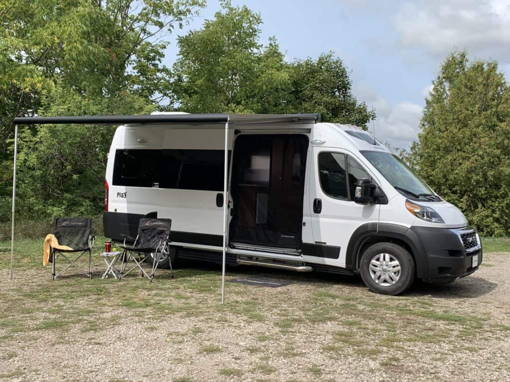 Roadtrek RV fully opened with awning extended at camp.