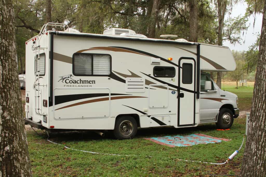 Class C RV provides Temporary Housing on a wooded lot.