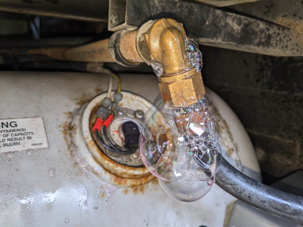 Propane leak detector spray bubbling on a LP hose to show a small propane leak.