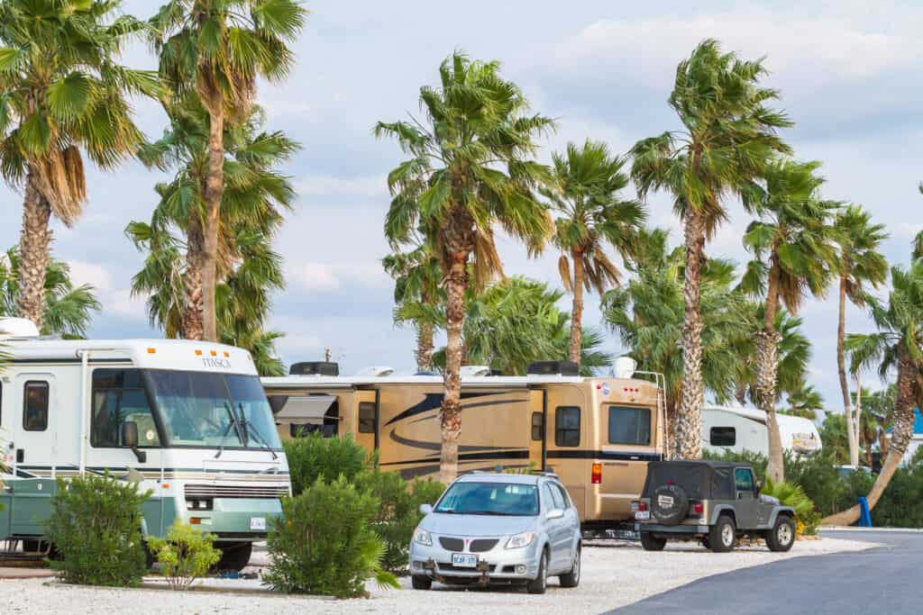A crowded campground with motorhomes, cars, and trailers.