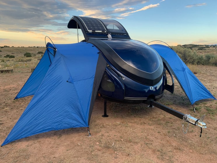 Teardrop travel trailer with attached side tents.