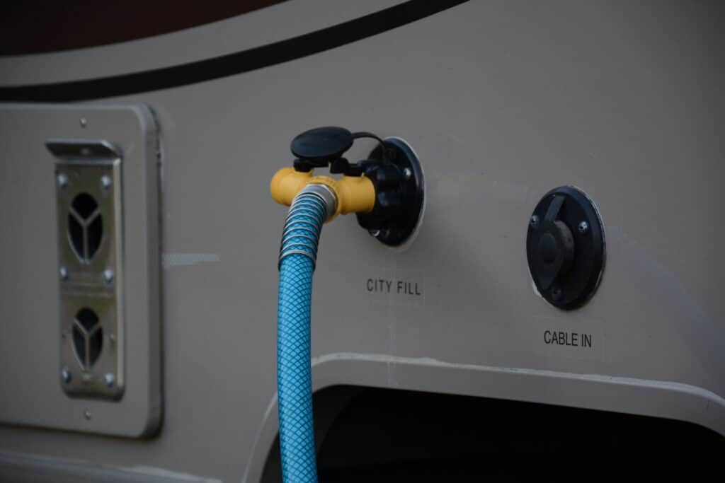 RV water hose connected to a T on the RV city fill hookup