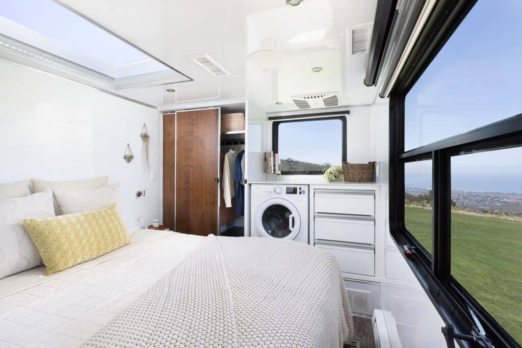 interior view of Living Vehicle luxury travel trailer bedroom with queen bed, closet and washer/dryer