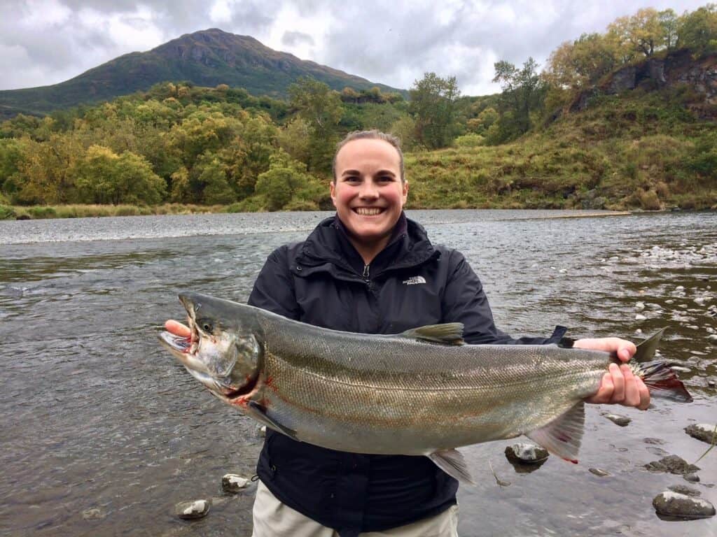 Successful Salmon fisherwoman holding large salmon.