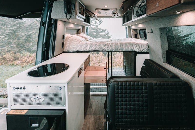 The interior of a Storyteller Overland camper van features a galley,  a Dreamweaver bed with a convertible work surface, and a Groovelounge two-seat convertible sofa bed, among other features.
