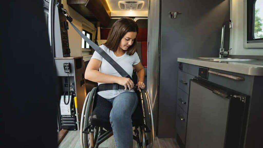 woman in wheelchair putting on seatbelt inside RV