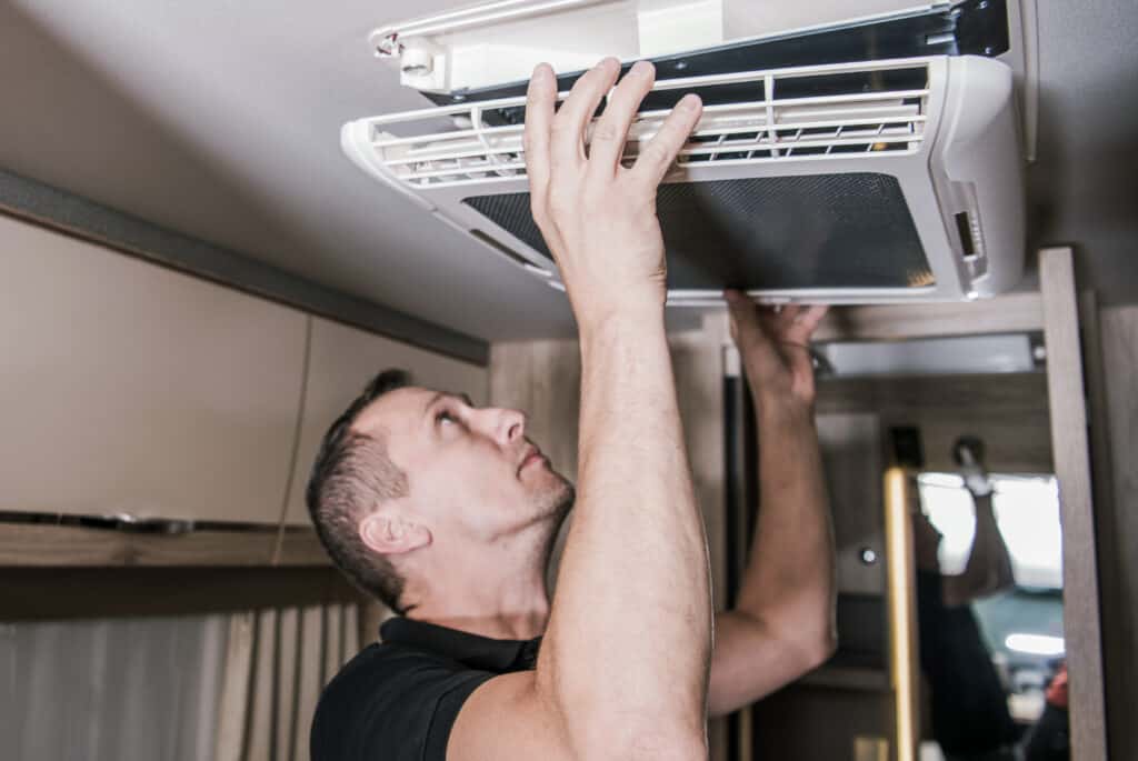 Man working on an RV air conditioner - pitfalls of renting out your RV