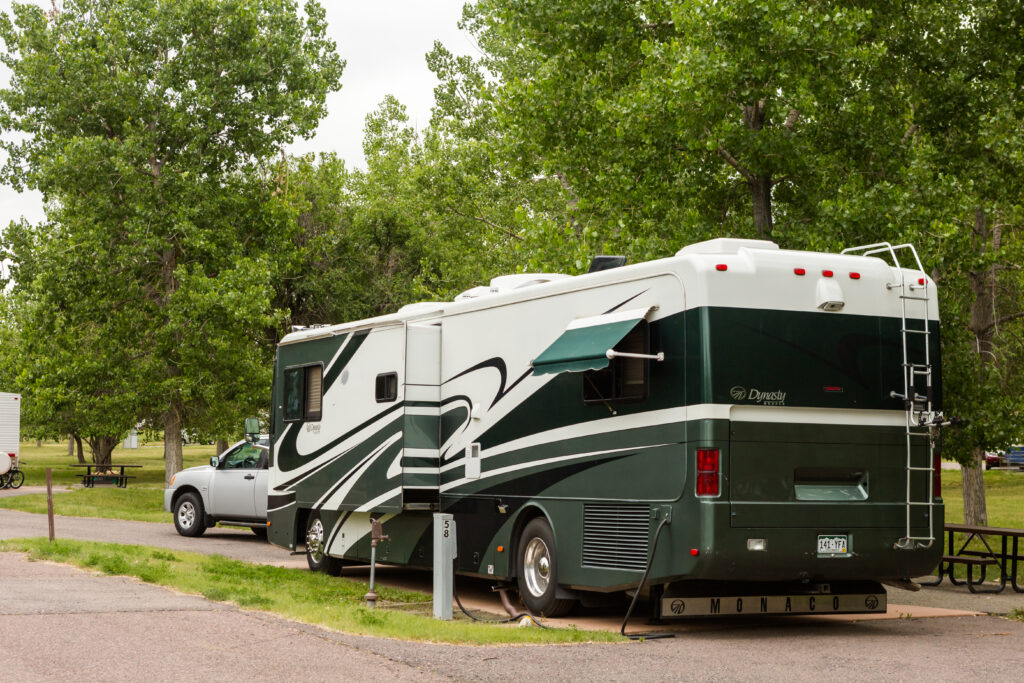 motorhome and tow vehicle in campsite - Class A vs Class C Motorhome: What's Right For You?