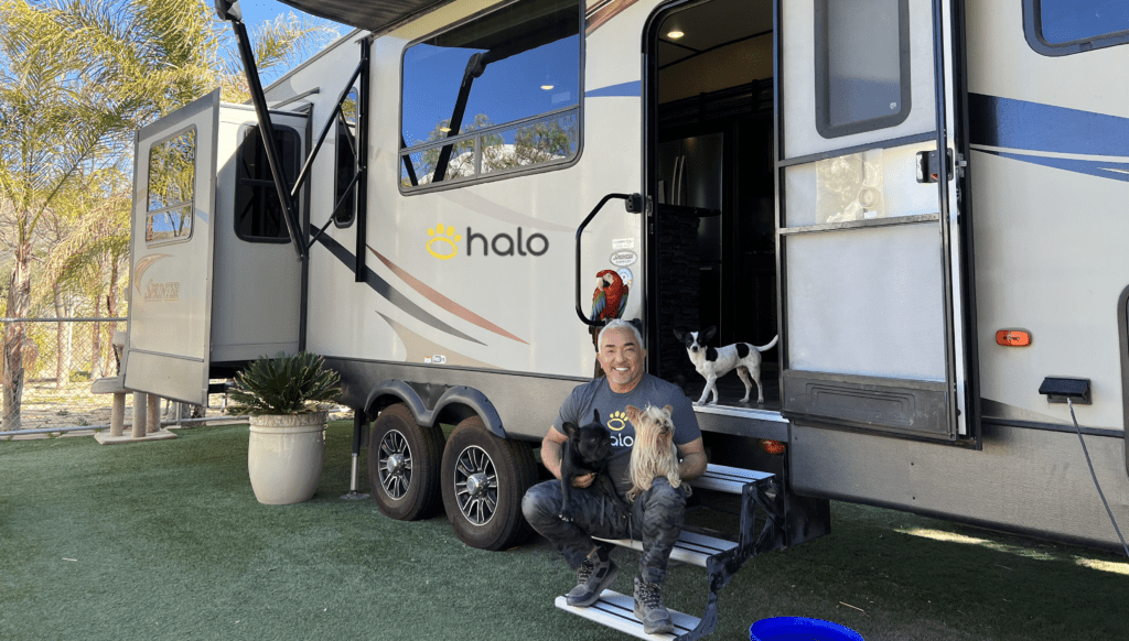 Cesar Milan in front of his RV with dogs and bird.