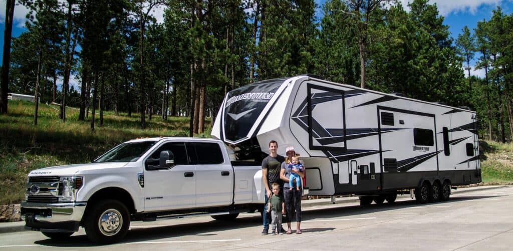 Family with children stan in front of white pick up truck with RV