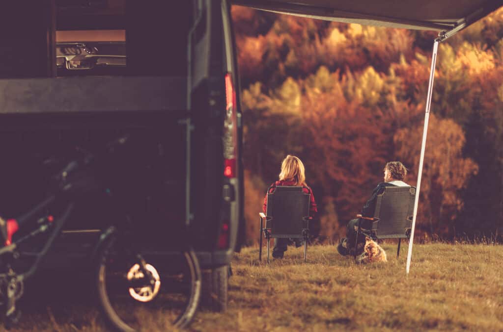 mini motorhomes with couple and dog outside under awning
