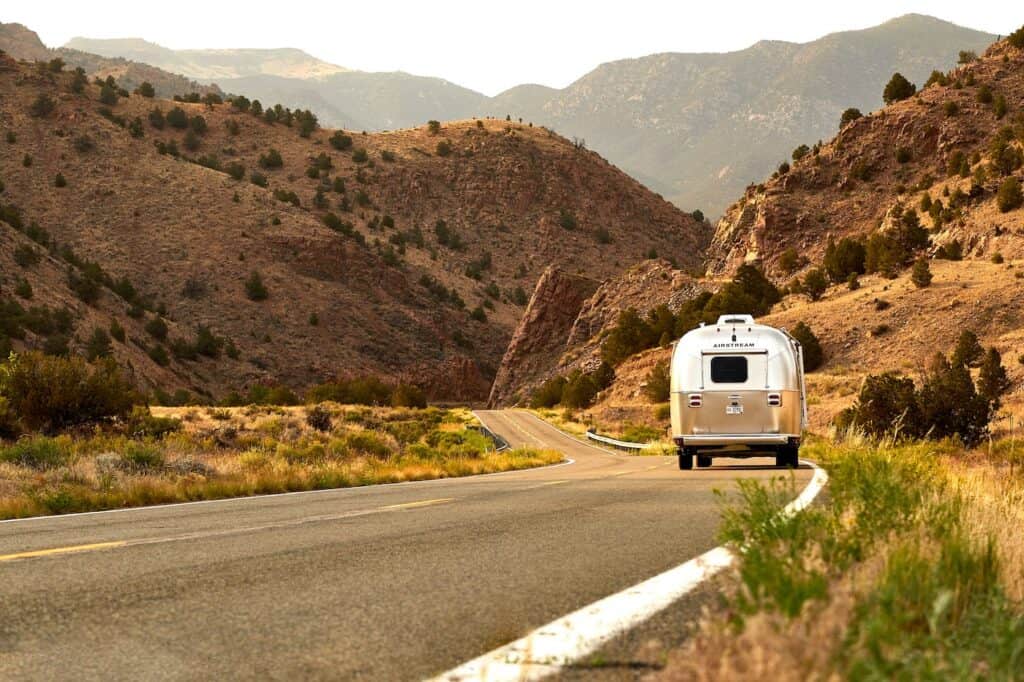 Airstream RV on mountainous desert road.