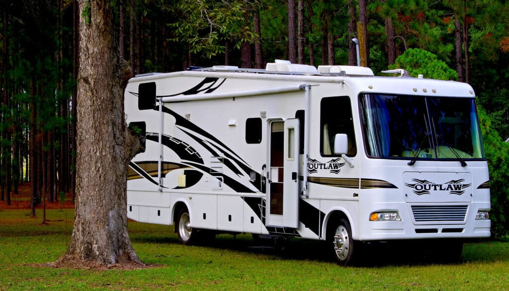 a Class A motorhome by Outlaw park under some pine trees