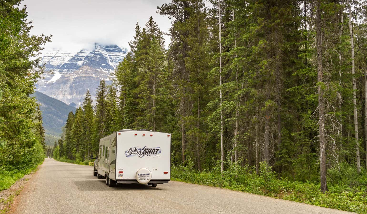 RV traveling in Canada through foreste with mountain view - feature image for Can I Travel to Canada in My RV?