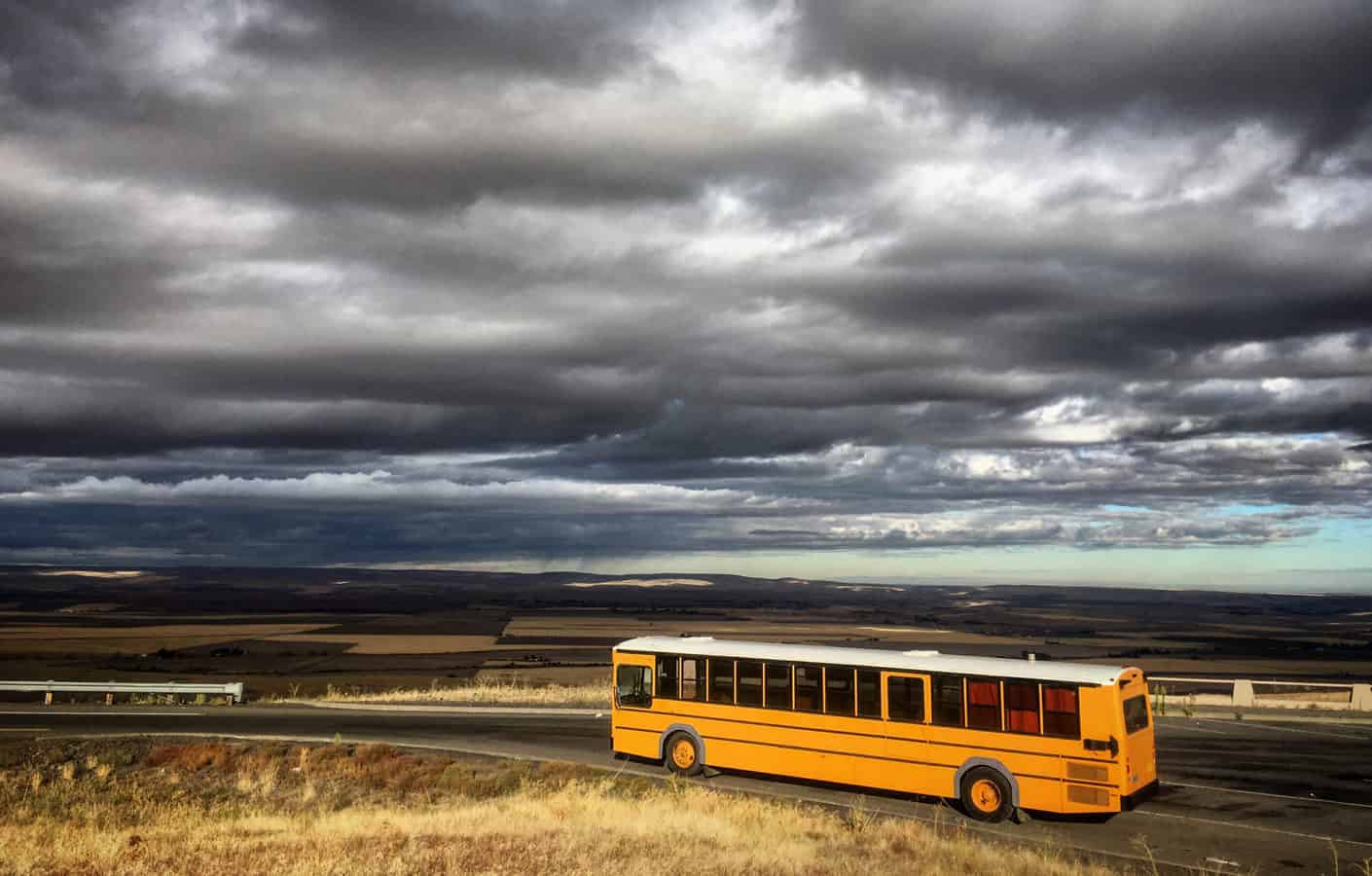 school bus RV under dark clouds - feature image for How To Turn A Bus Into An RV