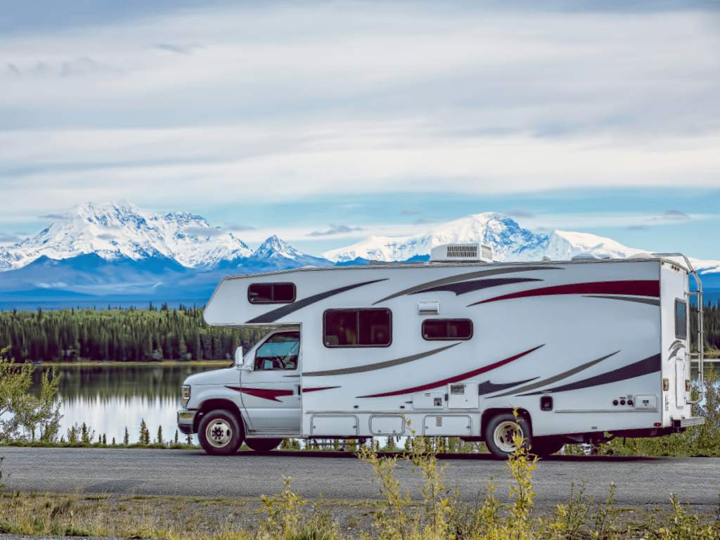 A Class A Motorhome parked in front of snow-capped mountains.