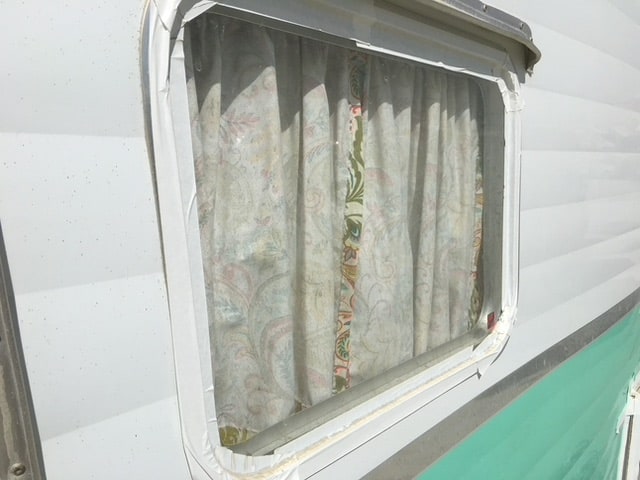 Window of classic teardrop trailer is taped to keep dust out.