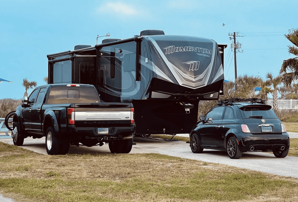 RV site holds a Grand Design Momentum 397TH , a small Fiat car, and a Ford F250.