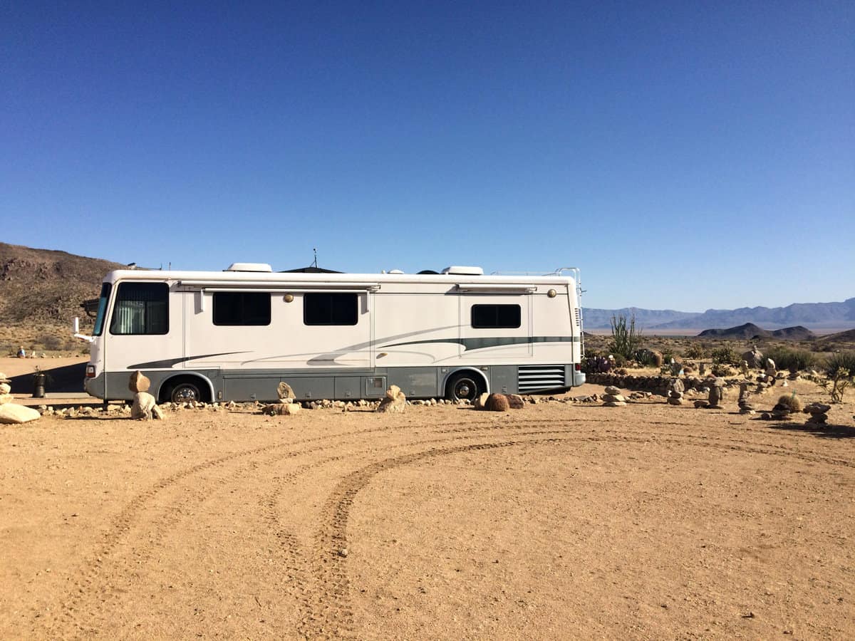 Class A motorhome parked in a desert parking area.