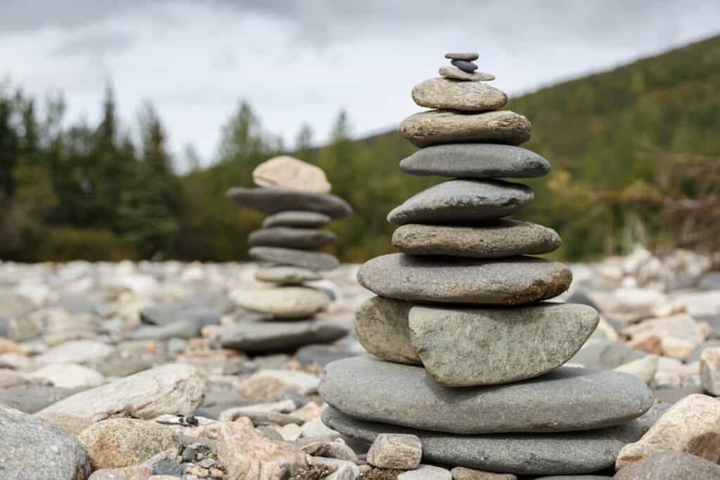 Stacks of Rocks on dry riverbed with forest behind