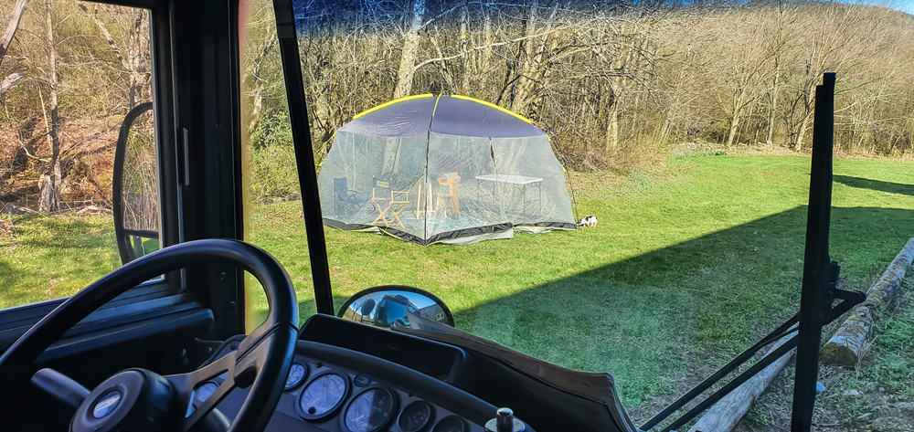 Looking through an RV windshield at a covered picnic table setting.