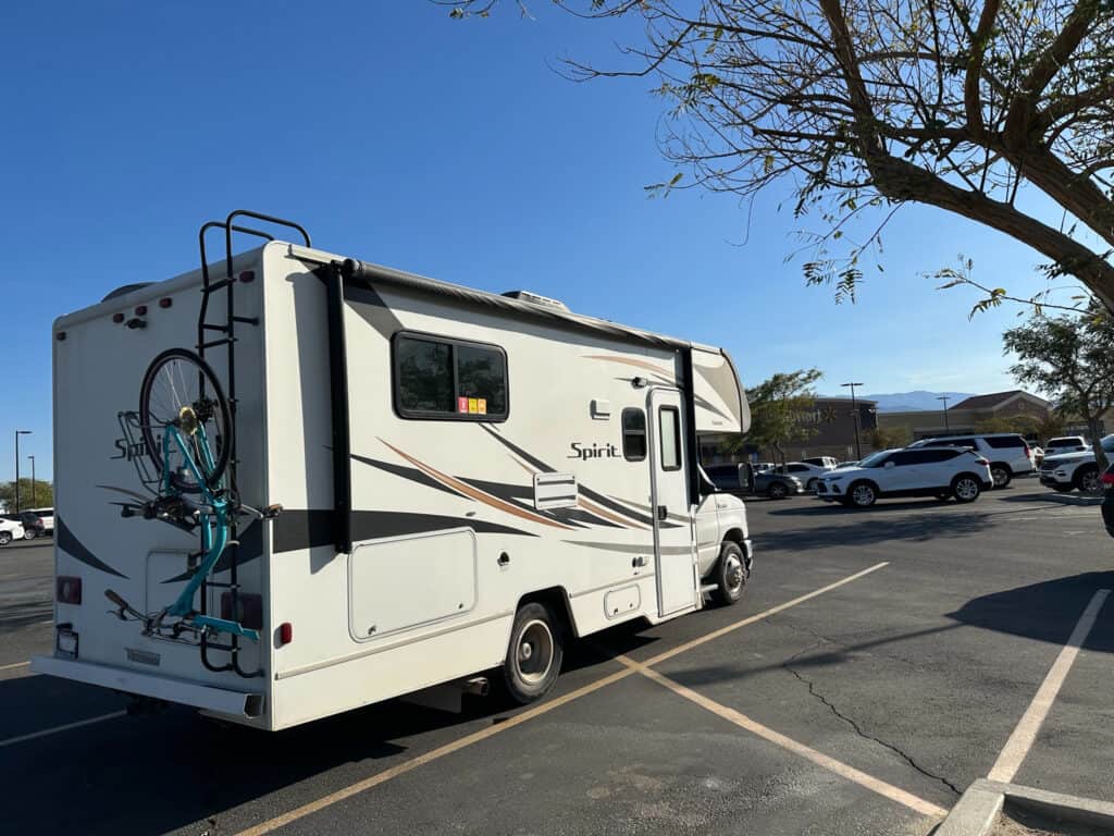 a camper parked in a parking lot next to a tree with a bicycle on the front of it, image for RV depreciation