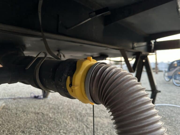 A sewer hose attached to the rv holding tanks on an rv, ready to be emptied.
