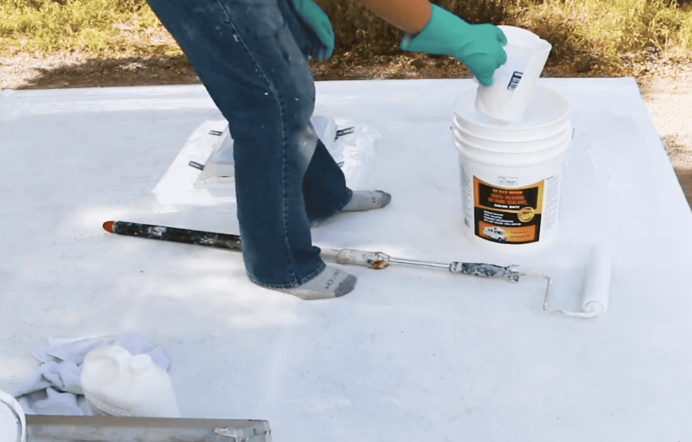 Man applies RV roof coating with a roller.
