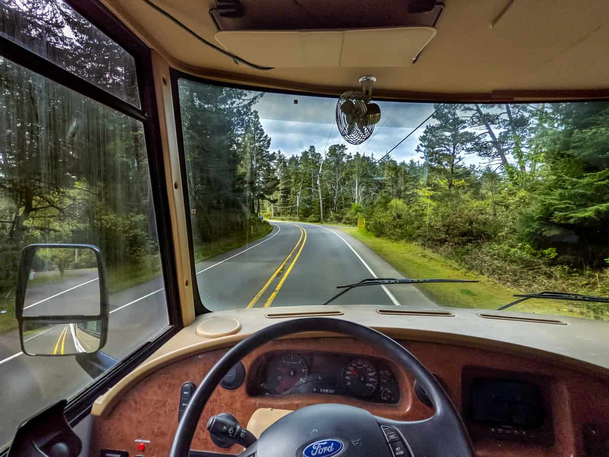 a view from the inside of a bus looking at a road with trees on both sides of the road, image for self driving