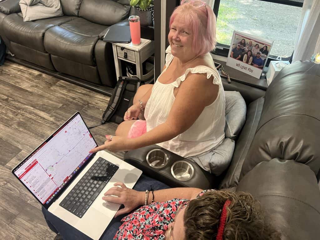 Two women on a couch working on a laptop.