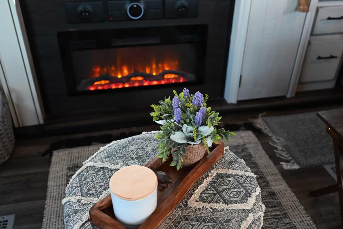 An electric RV fireplace burns in a cozy 5th wheel
