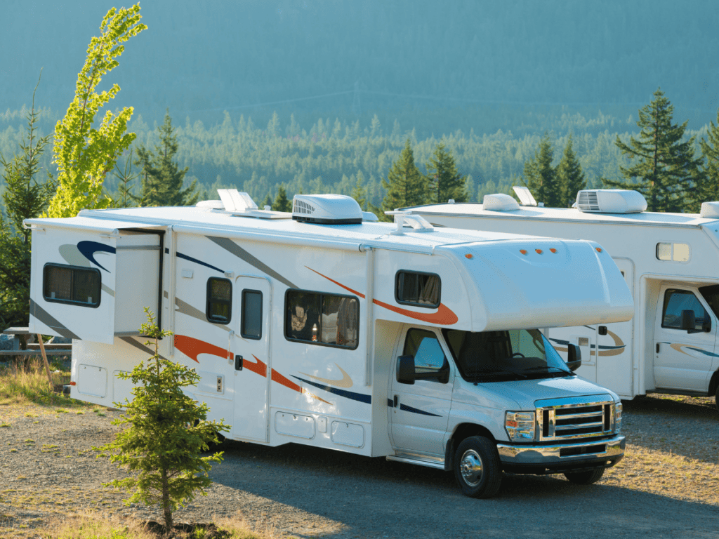 A class C motorhome sits in a wooded lot.