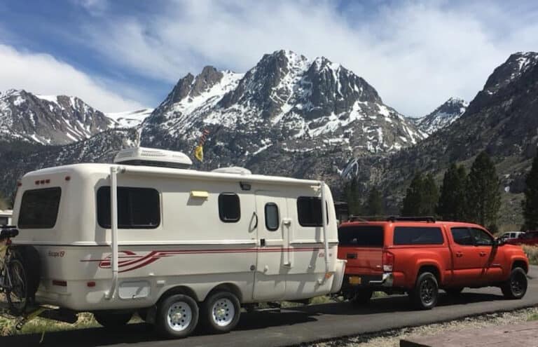 a truck connected to a fiberglass rv in a beautiful winter mountain campsite