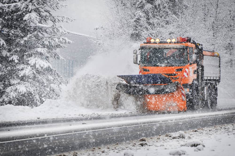 large snowplow cleaning roads during a winter storm in preparation of drivers.