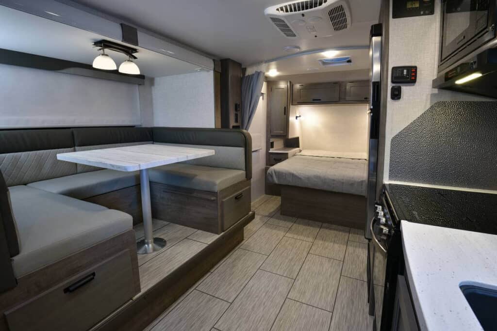 Interior of Squire travel trailer with large dinette and residential queen bed.