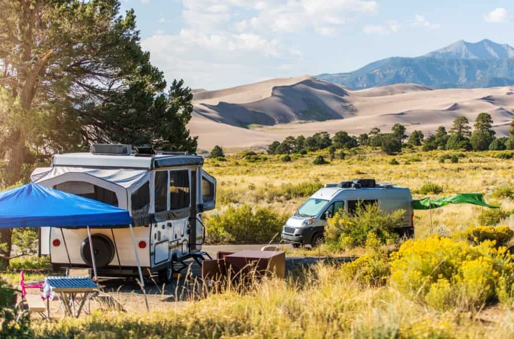 A camper van and pop-up trailer enjoying a national park visit at Colorado Great Sand Dunes NP.