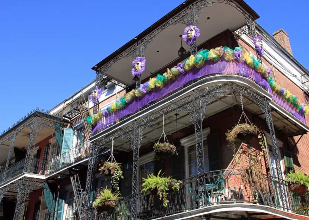 French Quarter wrought iron balconies decorated in yellow, purple, and aqua for Mardi Gras.
