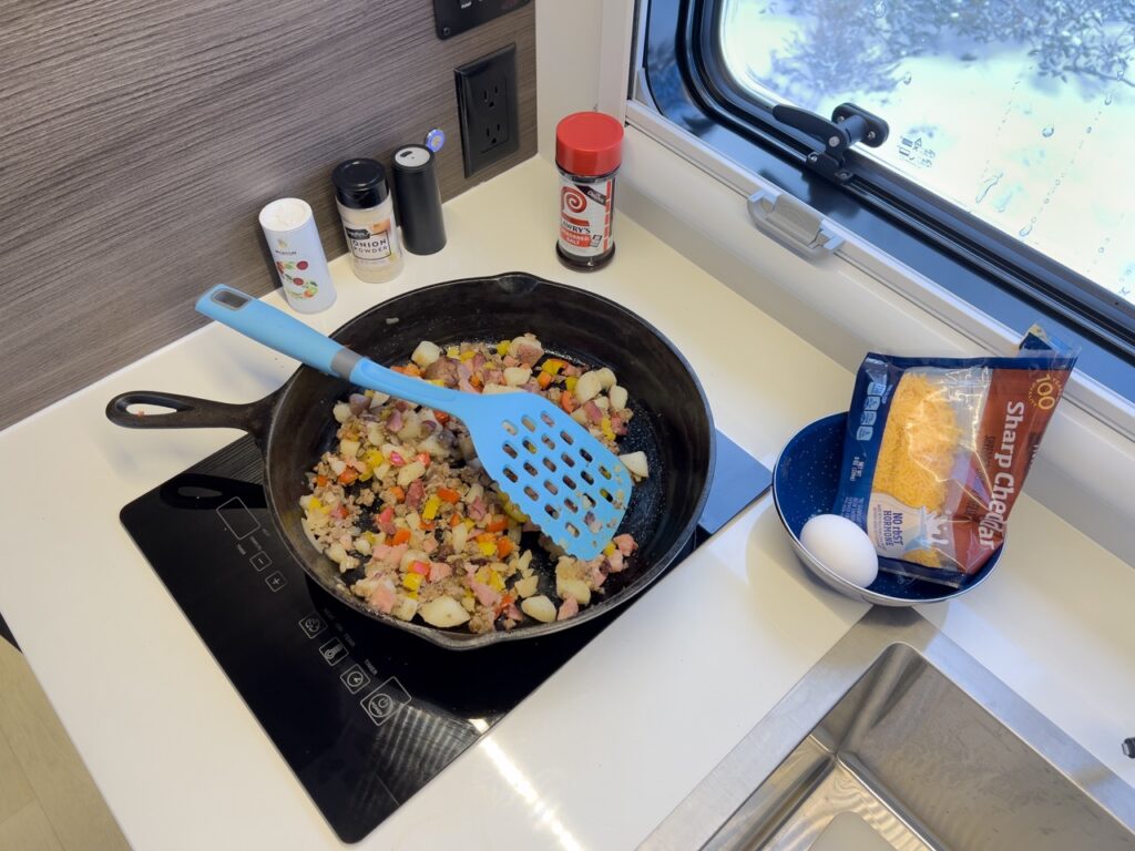 An induction cooktop in an RV, cooking a potato hash breakfast.