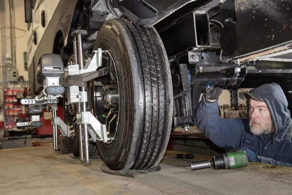 An RV technician performing a wheel and axle alignment on a trailer. Photo: Bruce Smith.